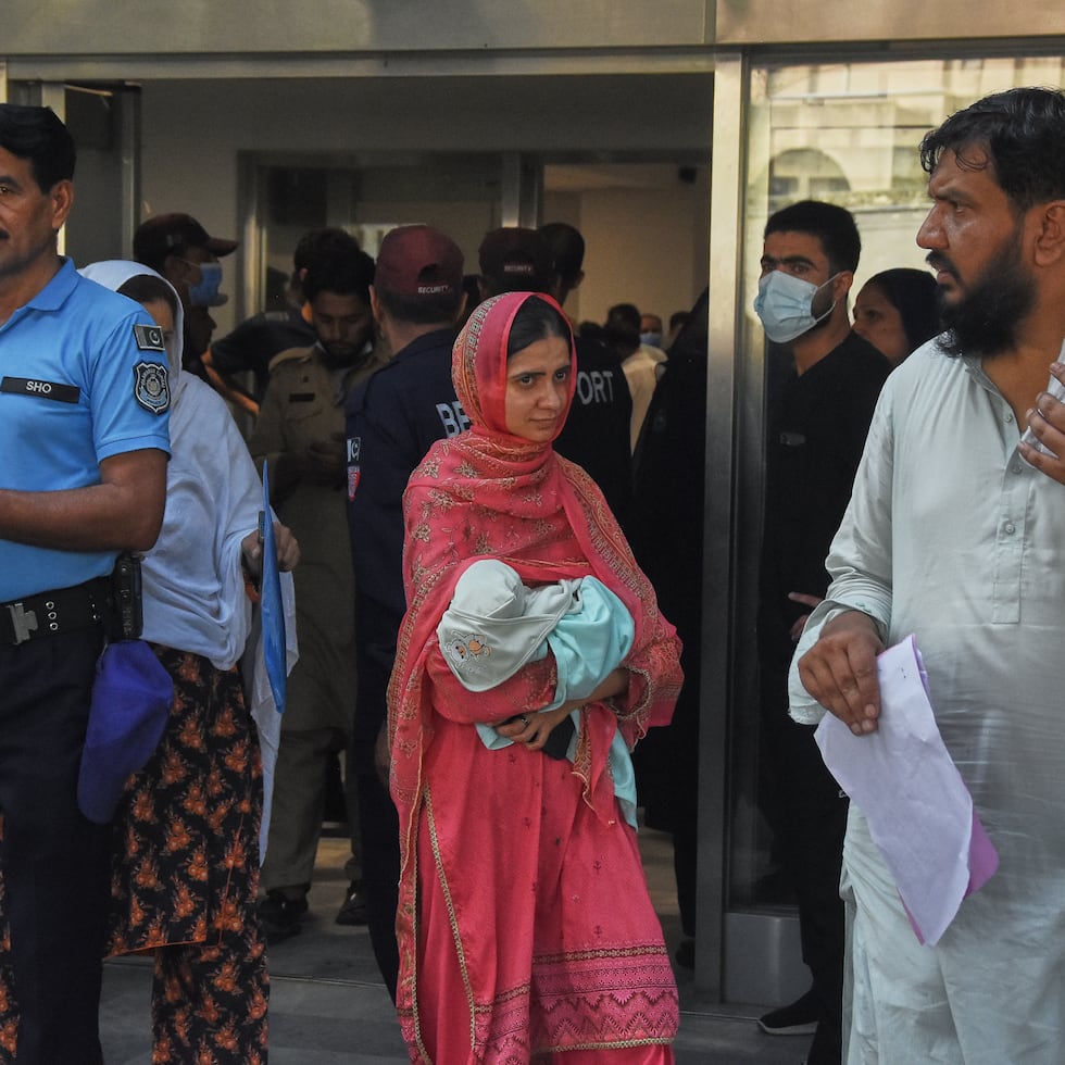 Una mujer lleva a su bebé en brazos al salir de una guardería en la sala de ginecología de un hospital tras un incendio, en Islamabad, Pakistán.