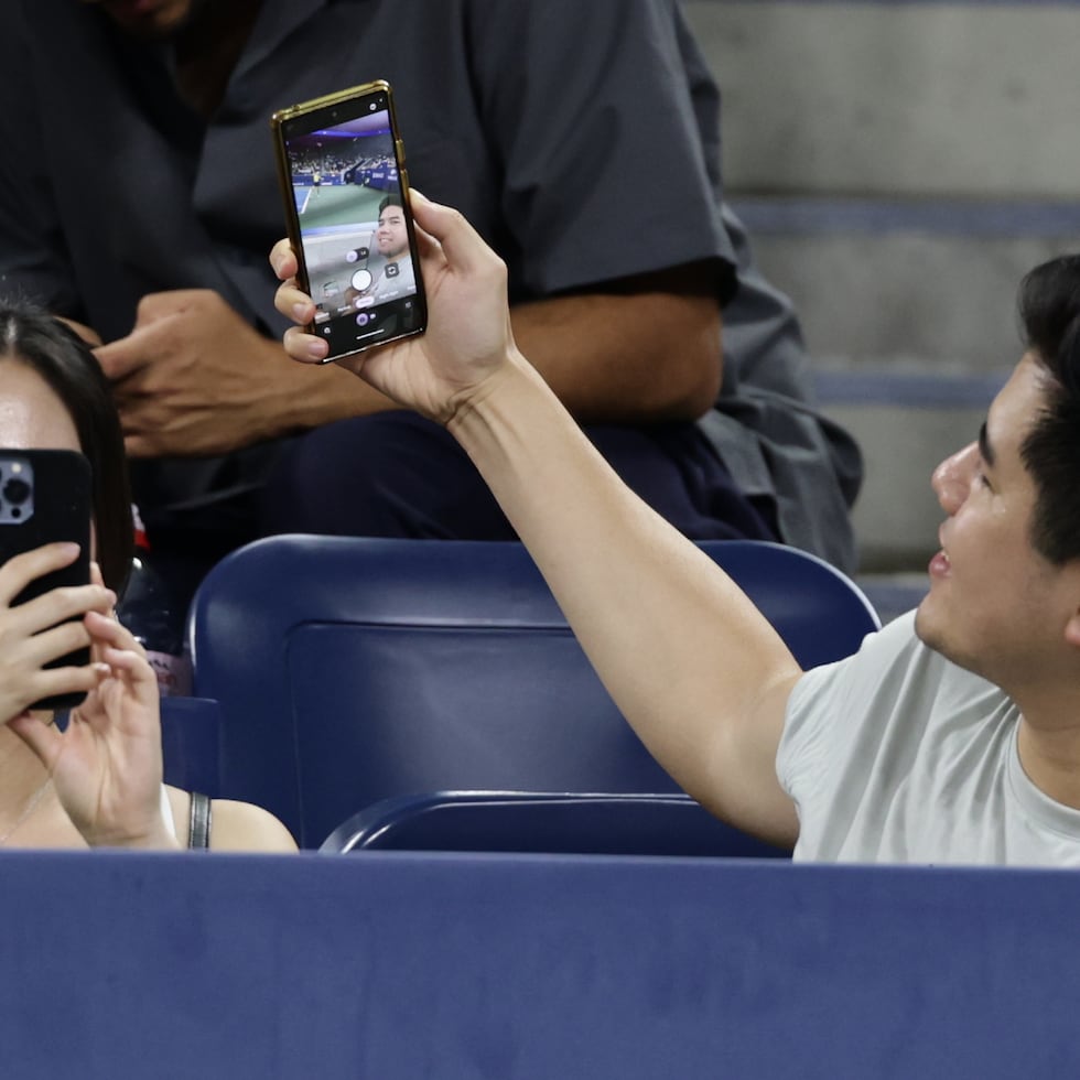 Un aficionado se toma una selfie mientras la kazaja Elena Rybakina sirve ante la española Jessica Bouzas Maneiro durante la segunda ronda del Abierto de Estados Unidos.
