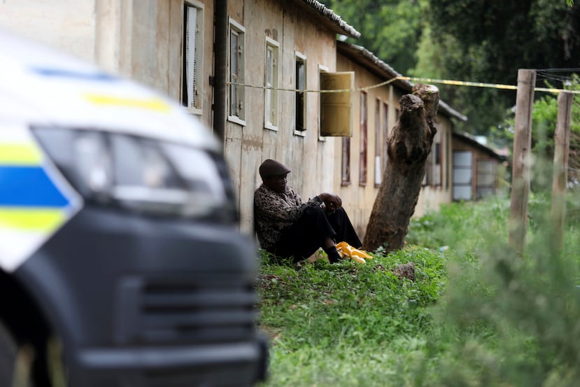 Un hombre se sienta afuera del lugar donde se encontraron los cuerpos de las víctimas de un tiroteo masivo, en un bar cerca de Pretoria, Sudáfrica, el sábado 6 de diciembre de 2025. (Foto AP/STR)