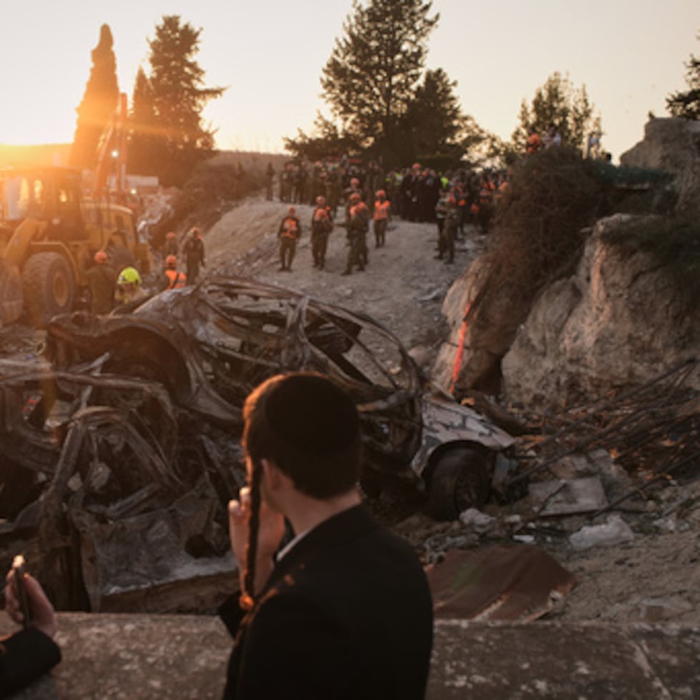Hombres judíos ultraortodoxos miran mientras las fuerzas de seguridad israelíes operan en el lugar donde varias personas murieron en un ataque con misiles iraníes en Beit Shemesh, Israel, el domingo 1 de marzo de 2026. (AP Photo/Leo Correa)