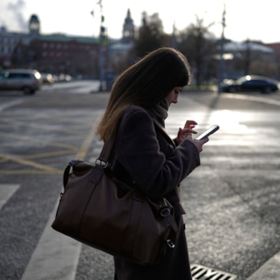 Una mujer mira su smartphone en el centro de Moscú, Rusia, el jueves 20 de noviembre de 2025. (AP Photo/Alexander Zemlianichenko)