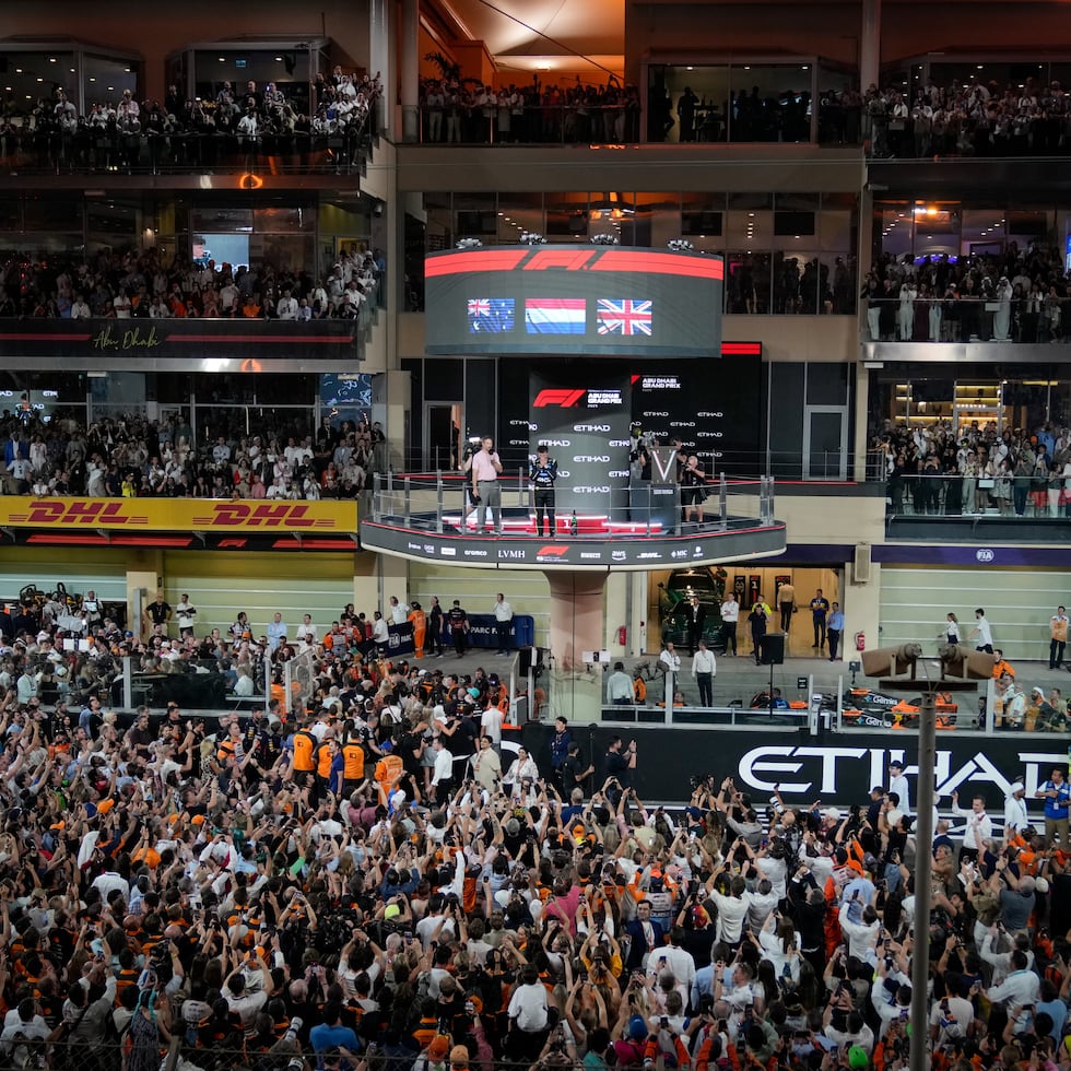 La multitud estalla mien.tras el piloto británico de McLaren, Lando Norris, reacciona en el podio tras convertirse en campeón mundial de la Fórmula Uno luego del Gran Premio de Abu Dabi