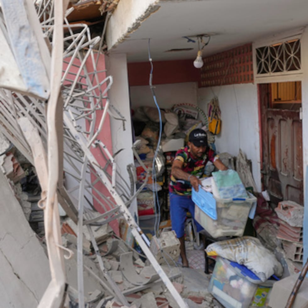 Jonathan Mayoral ayuda a sus familiares a limpiar su apartamento, que los residentes dicen que fue dañado durante las operaciones militares estadounidenses para capturar al presidente venezolano Nicolás Maduro, en Catia La Mar, Venezuela, el domingo 4 de enero de 2026. (AP Photo/Matias Delacroix)