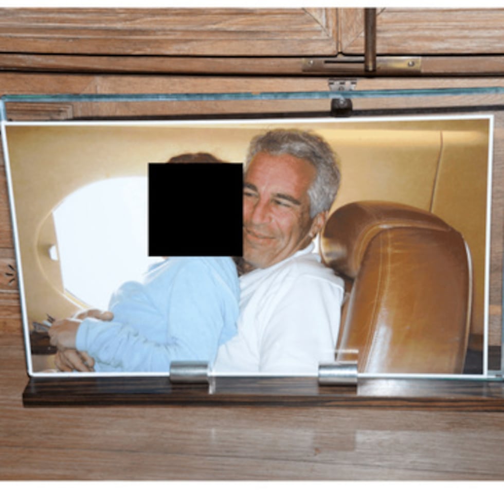 Esta foto recién publicada por el Departamento de Justicia de Estados Unidos muestra una fotografía enmarcada de Jeffrey Epstein con una persona en su regazo.