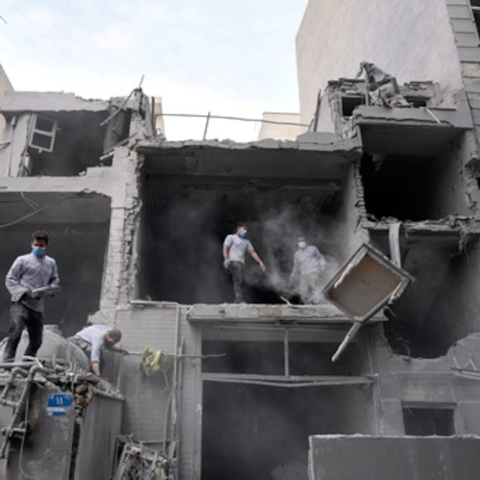 Voluntarios limpian los escombros de un edificio residencial dañado cuando una comisaría cercana fue alcanzada en un ataque estadounidense-israelí en Teherán.