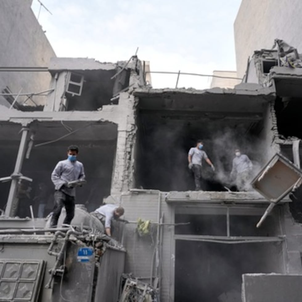 Voluntarios limpian los escombros de un edificio residencial dañado cuando una comisaría cercana fue alcanzada el viernes en un ataque estadounidense-israelí en Teherán, Irán, domingo 15 de marzo de 2026. (AP Photo/Vahid Salemi)