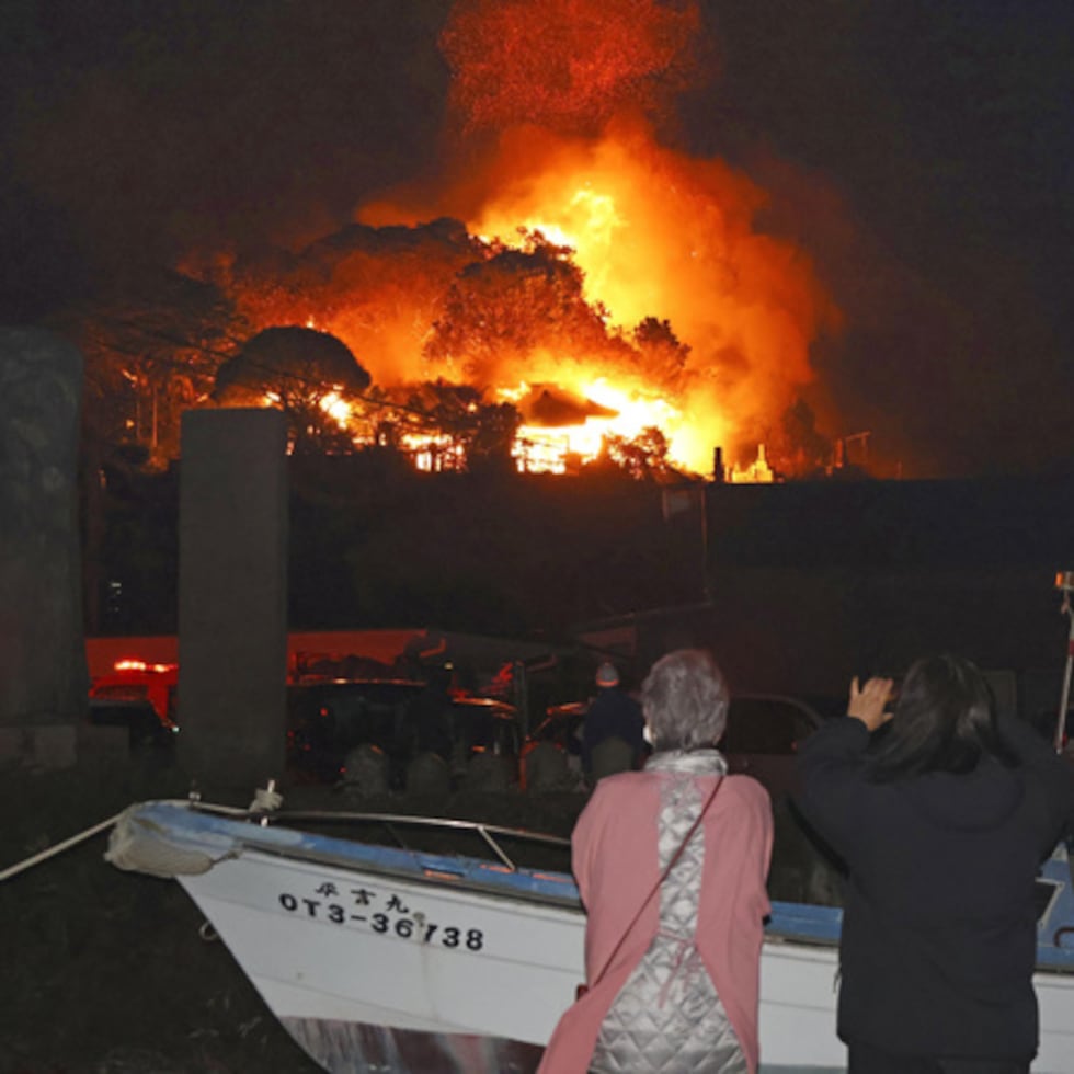 Residents watch flames rise from the site of a fire in Oita, southern Japan Tuesday, Nov. 18, 2025. (Kyodo News via AP)