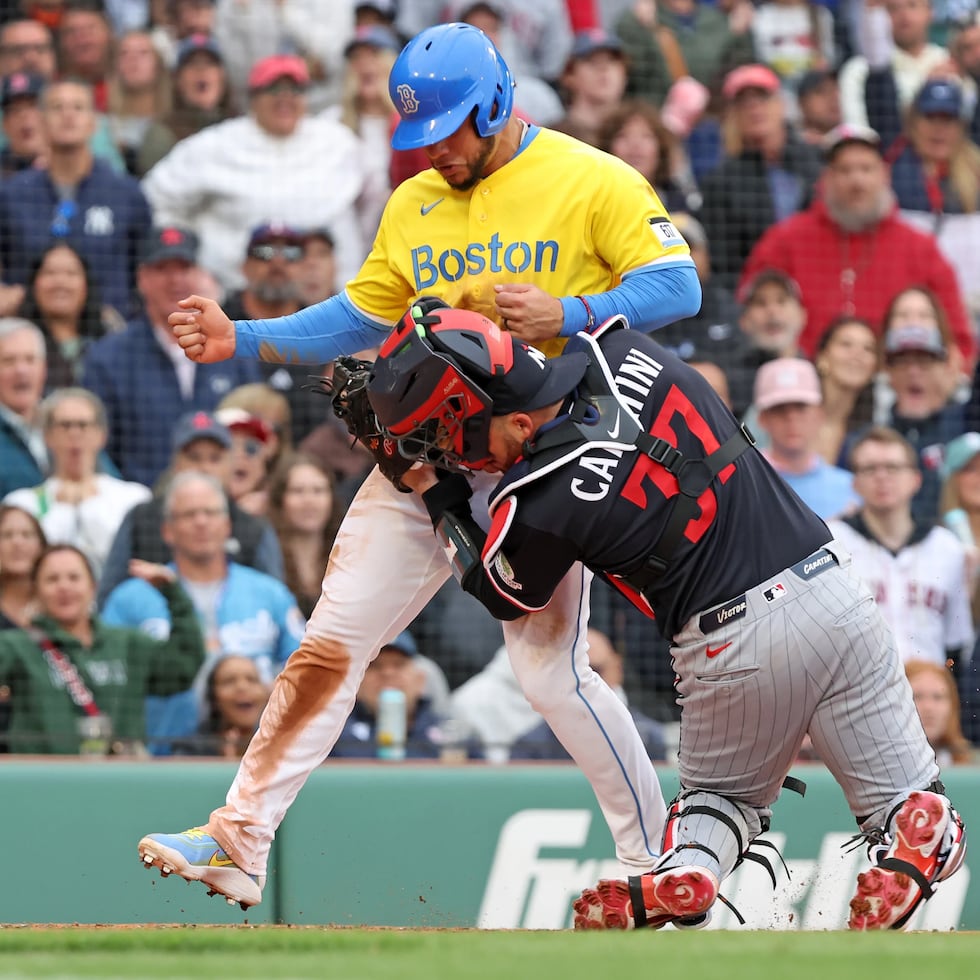 El receptor coameño de los Twins de Minnesota, Víctor Caratini, recibe el impacto de Willson Contreras, de los Red Sox de Boston, durante una colisión en el plato en el partido del sábado.
