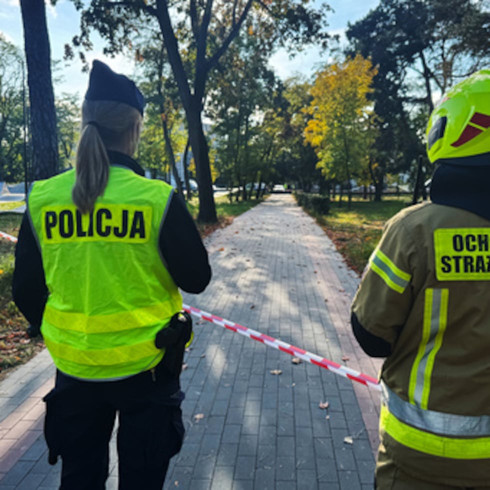 Un agente de policía y un bombero voluntario observan la calle cerca de una zona acordonada tras un atentado contra el Complejo de Formación Profesional n.º 4 en Ostroleka, Polonia, el miércoles 7 de octubre de 2026. (Foto AP/Rafal Niedzielski)