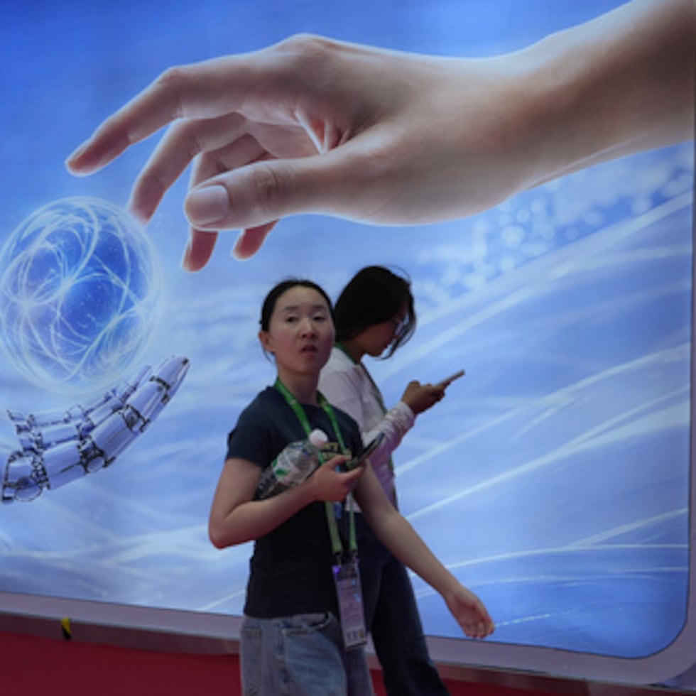 Los visitantes pasan junto a una exposición que muestra la inteligencia artificial y una mano humana en la Exposición Internacional de la Cadena de Suministro de China, celebrada en Pekín en junio de 2026.