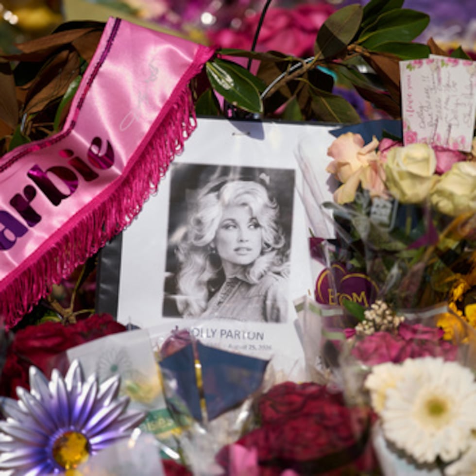 Un retrato de la difunta Dolly Parton, rodeado de flores y tarjetas en un homenaje, se encuentra frente a su casa el jueves 27 de agosto de 2026, en Brentwood, Tennessee. (Foto AP/George Walker IV)