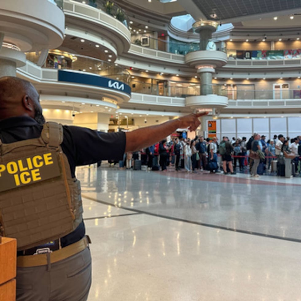 Un agente federal de inmigración es visto mientras la gente espera en una línea de TSA en el Aeropuerto Internacional Hartsfield-Jackson de Atlanta.