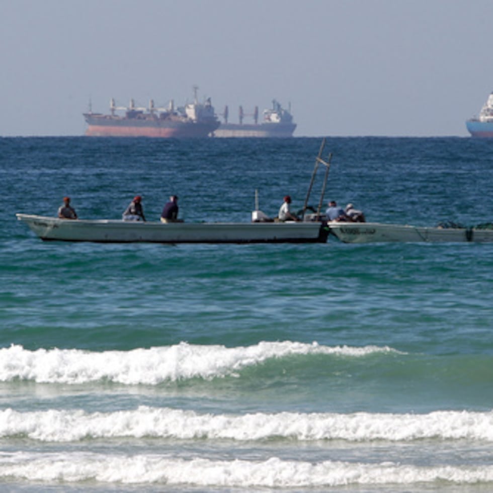 Pescadores trabajan ante un petrolero en el sur del estrecho de Ormuz, frente la costa de la localidad de Ras Al Khaimah en Emiratos Árabes Unidos.