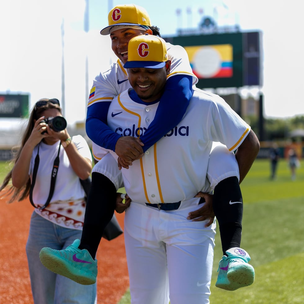 Guillo Zuñiga (66) jokes with teammate Michael Arroyo (8) during Colombia's practice at the Bithorn.