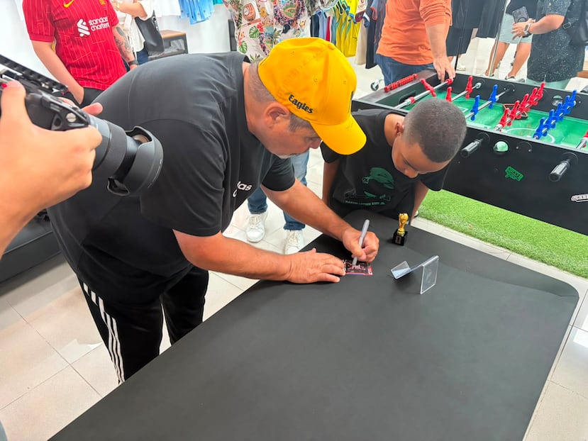 Mark Lugris firma tarjetas de colección durante la presentación de la pieza que inmortaliza su histórico gol con Puerto Rico en 1992.