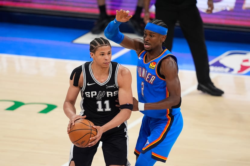 El delantero de los Spurs, Carter Bryant (11), disputa una jugada contra el base del Thunder, Shai Gilgeous-Alexander, a la derecha, durante el Juego 1 de las Finales de la Conferencia Oeste de los playoffs de la NBA.