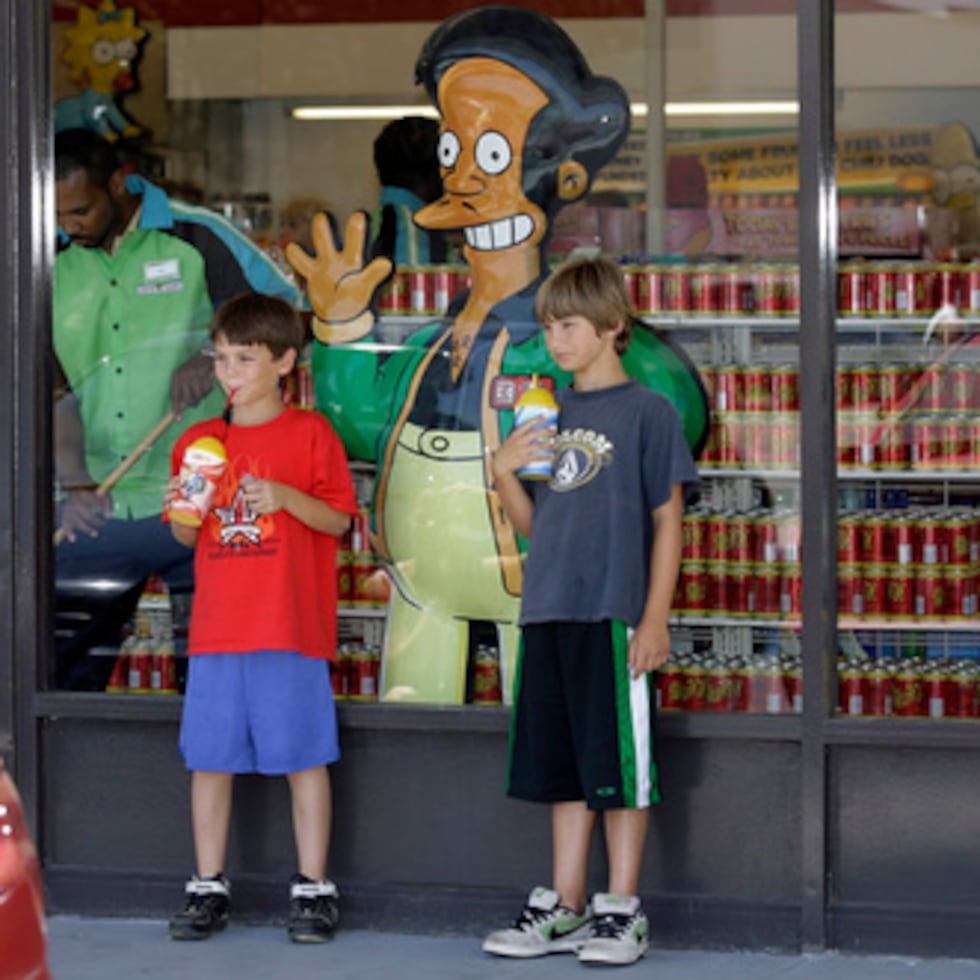 ARCHIVO - Unos niños posan junto a un escaparate en el que aparece Apu Nahasapeemapetilon Jr., personaje de «Los Simpson», frente a un 7-Eleven Kwik-E-Mart en Burbank (California), el 2 de julio de 2007. (Foto AP/Damian Dovarganes, archivo)