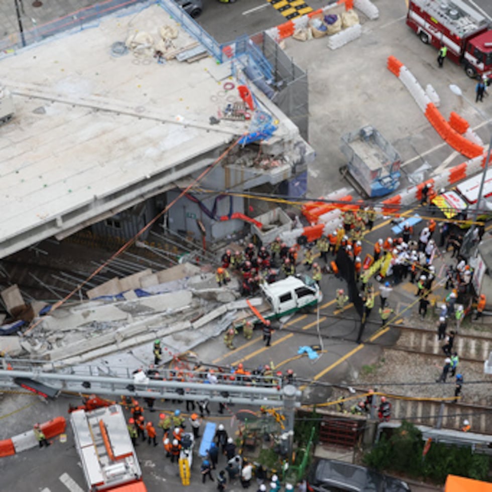 Bomberos y rescatistas surcoreanos tratan de buscar entre los escombros después de que un paso elevado se derrumbara parcialmente cuando se estaba desmontando en Seúl, Corea del Sur, el martes 26 de mayo de 2026.