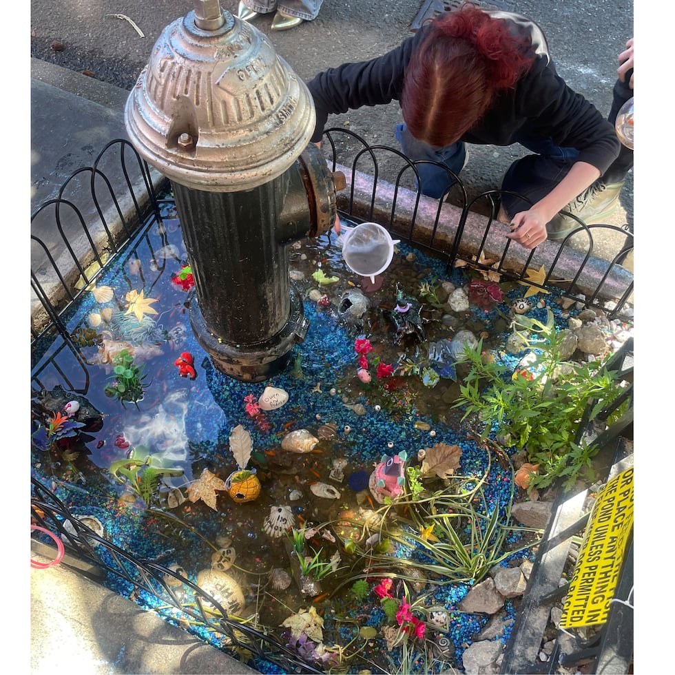 Una mujer cuida de un estanque de peces de colores improvisado, creado luego de que se formó un charco por una fuga en un hidrante contra incendios, el 8 de septiembre de 2024, en el distrito neoyorquino de Brooklyn.