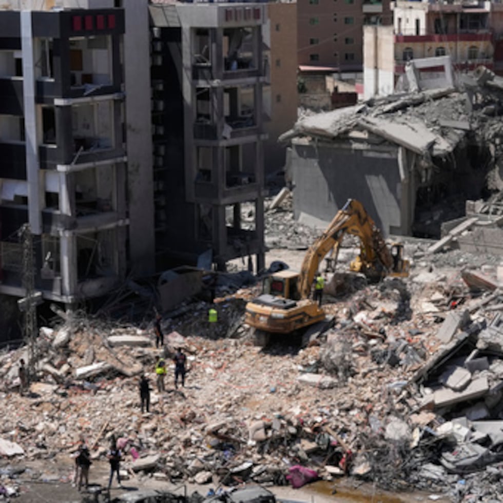 Los trabajadores de rescate utilizan una excavadora, mientras buscan víctimas bajo los escombros de un edificio que fue alcanzado el lunes en un ataque aéreo israelí en el sur de la ciudad portuaria de Tiro, Líbano.