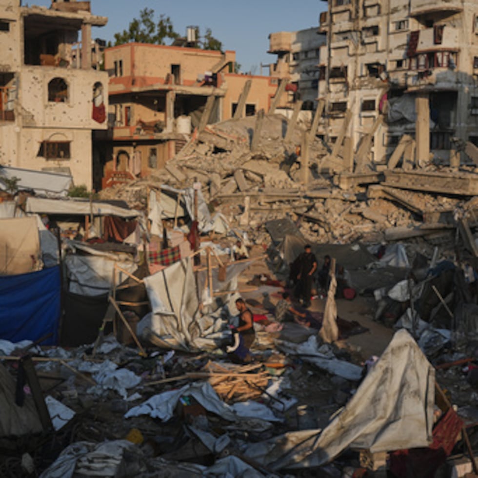 Palestinos rescatan sus pertenencias de entre los escombros de un edificio y unas tiendas de campaña destruidas en un ataque aéreo israelí en la ciudad de Gaza, el jueves 30 de julio.