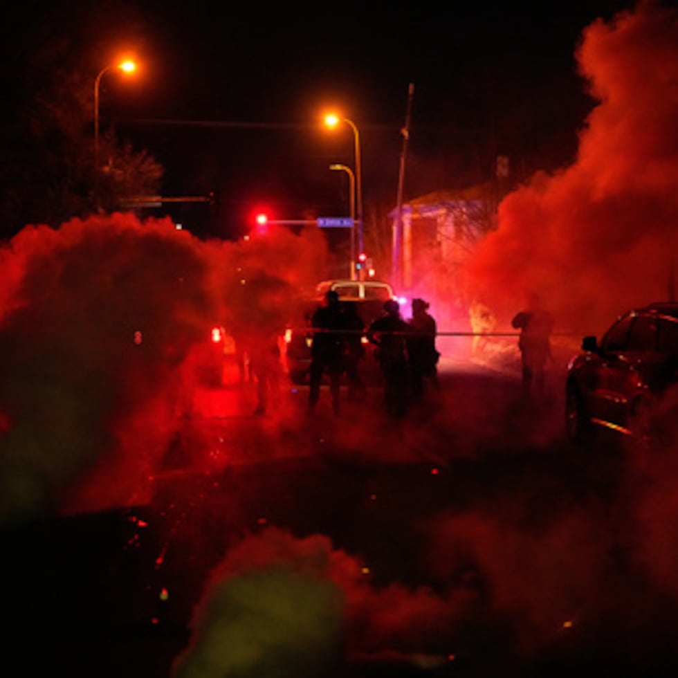 Agentes de la policía federal rodeados de gases lacrimógenos abandonan el lugar de los hechos tras un tiroteo el miércoles 14 de enero.