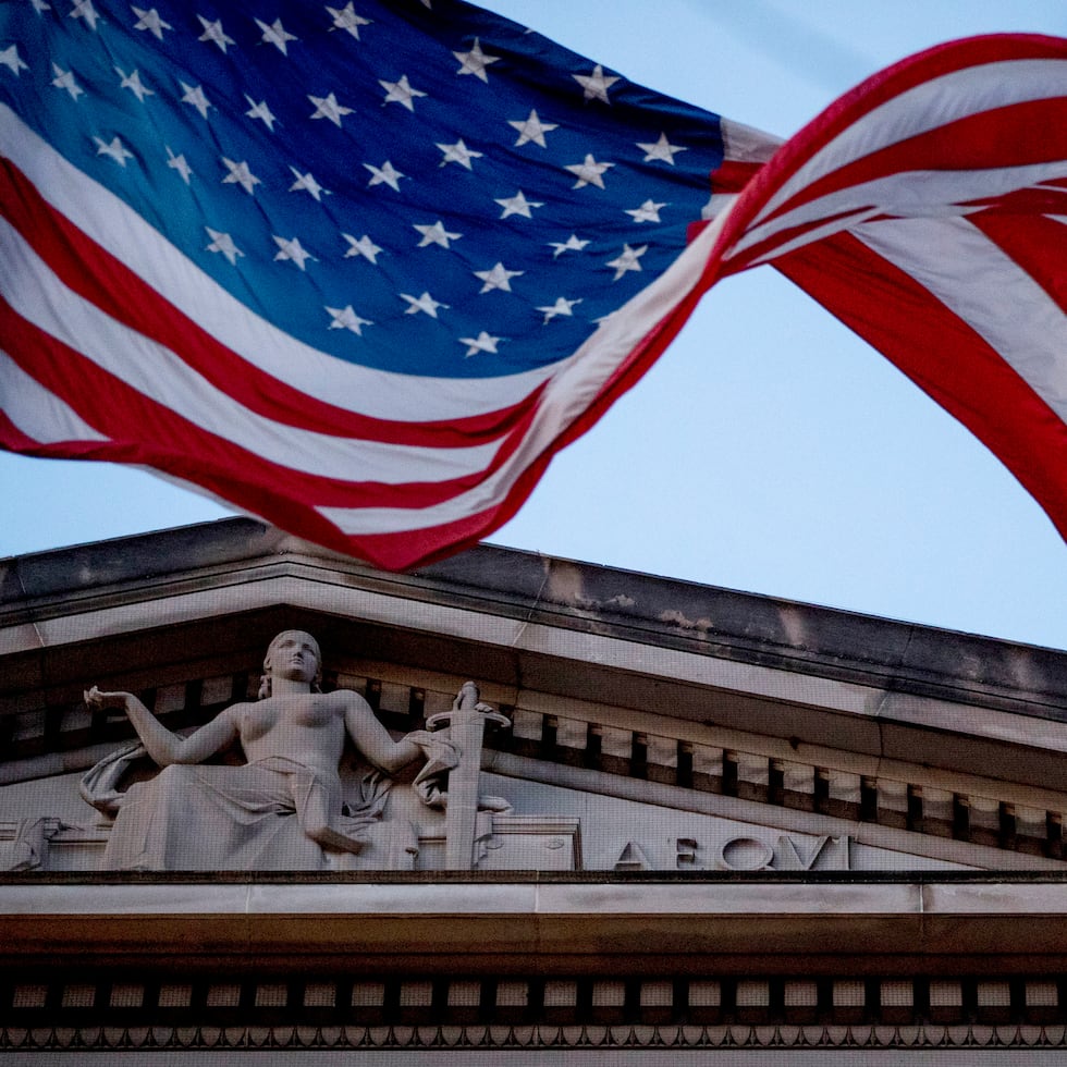 ARCHIVO - En esta foto del 22 de marzo del 2019, una bandera estadounidense ondea en la fachada del Departamento de Justicia en Washington. (AP Foto/Andrew Harnik)