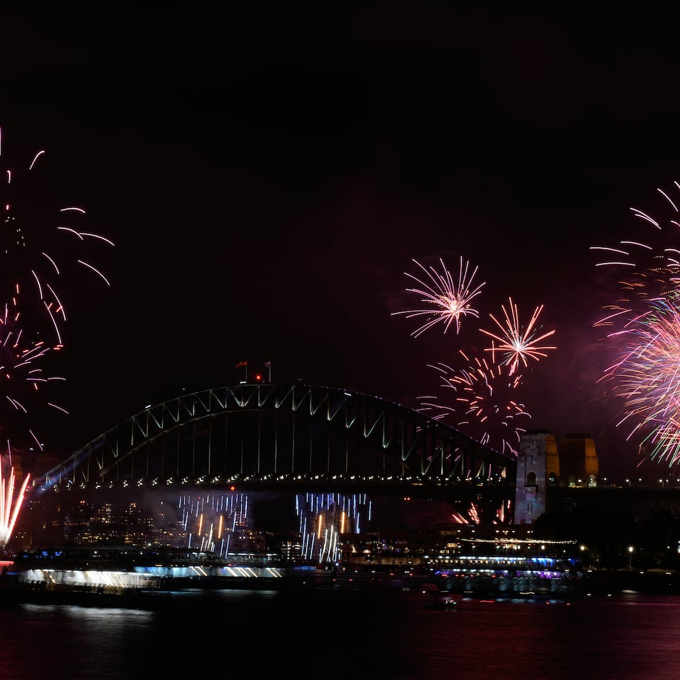 Fuegos artificiales estallan sobre el Puente del Puerto de Sídney al comenzar las celebraciones de Año Nuevo en Sídney.
