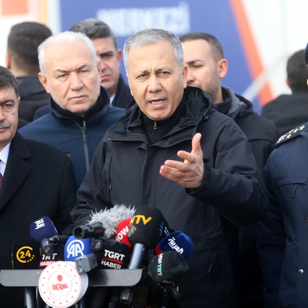 El ministro del Interior turco, Ali Yerlikaya, habla con los medios mientras el personal de la Autoridad de Gestión de Desastres y Emergencias busca entre los restos de un avión.