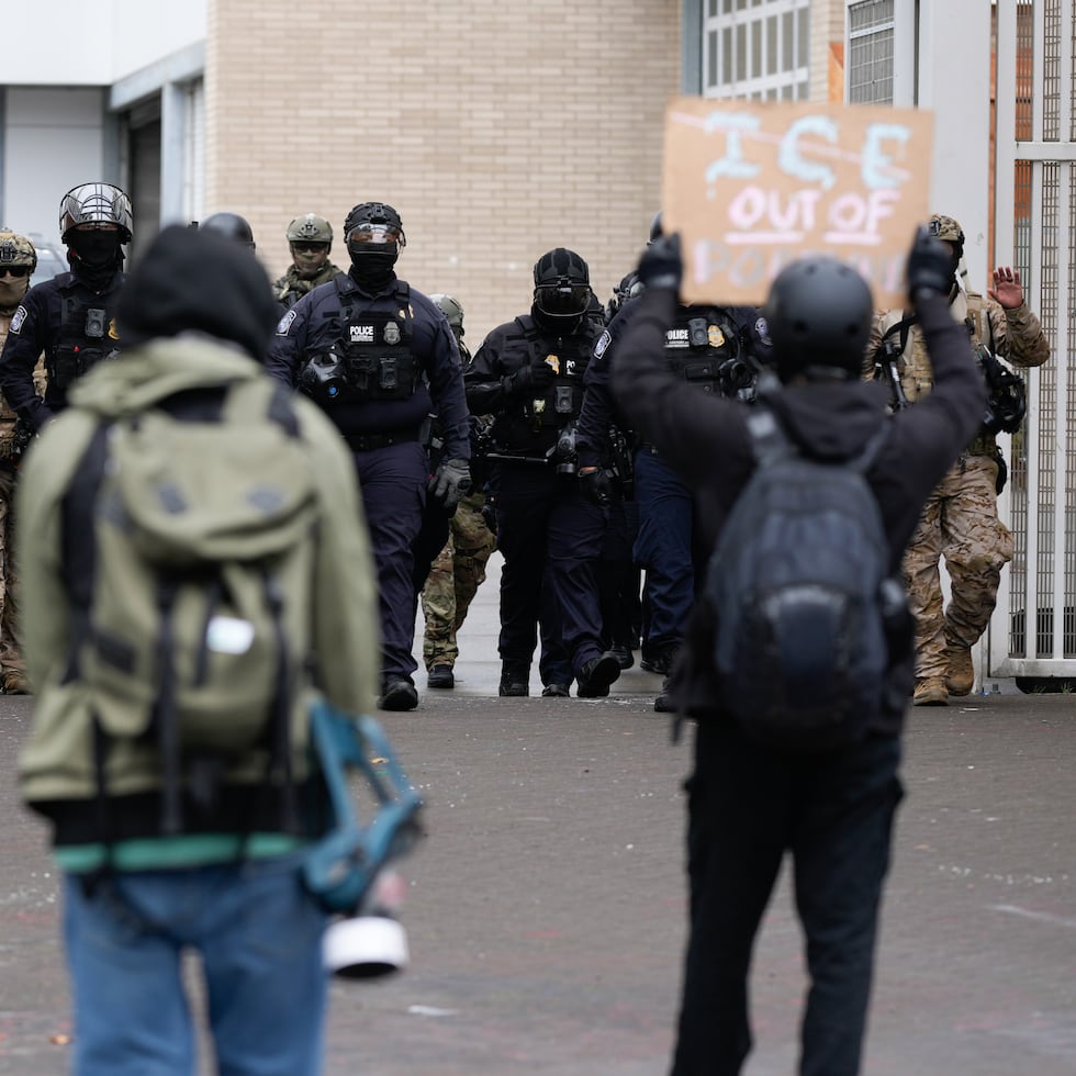 Personas protestan frente a una instalación del Servicio de Inmigración y Control de Aduanas de Estados Unidos mientras los agentes del orden salen por las puertas para custodiar los vehículos que abandonan la instalación el 11 de octubre de 2025 en Portland, Oregón.