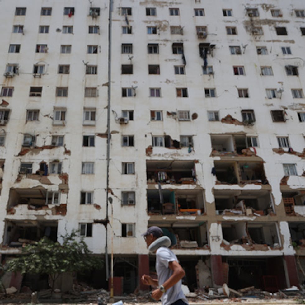 Un vecino pasa junto a un edificio dañado un día después de que un terremoto y varias réplicas sacudieran La Guaira, Venezuela.