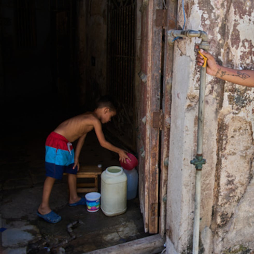 Un joven recoge agua en la planta baja de un edificio de viviendas, durante un apagón que dejó fuera de servicio la bomba de agua, en La Habana.