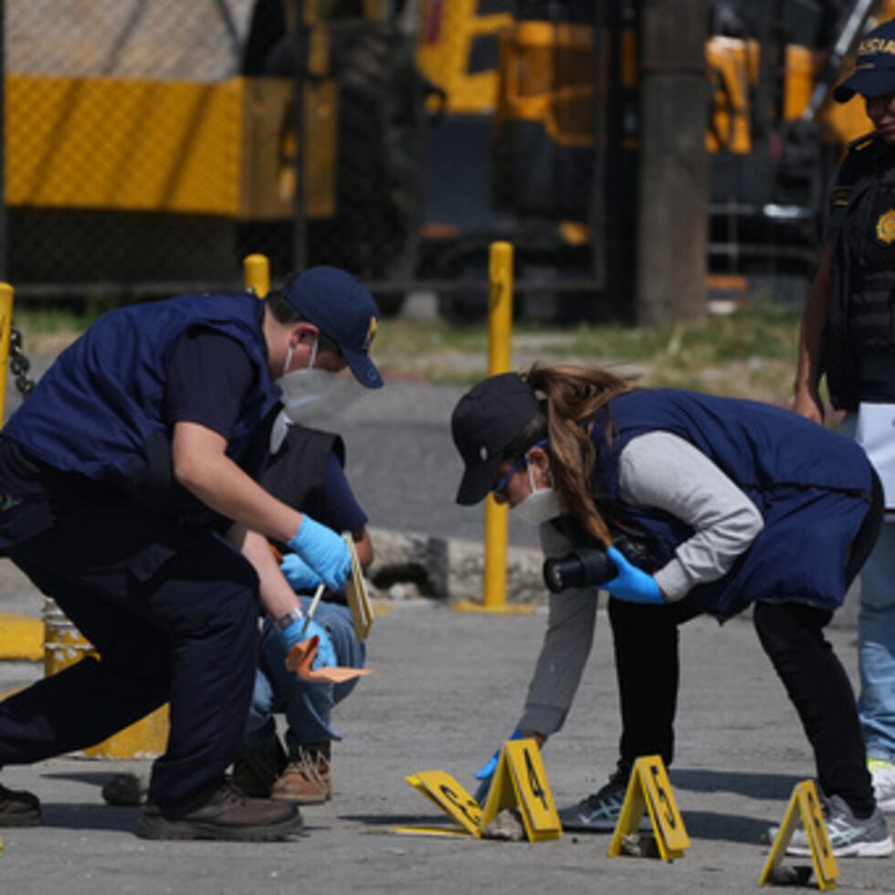 Investigadores forenses colocan marcadores de pruebas en el lugar donde murieron agentes de policía en ataques registrados después de que las fuerzas de seguridad retomaran el control de una prisión que alberga a líderes de pandillas, en Villanueva, en las afueras de Ciudad de Guatemala, el domingo 18 de enero de 2026. (AP Photo/Moises Castillo)