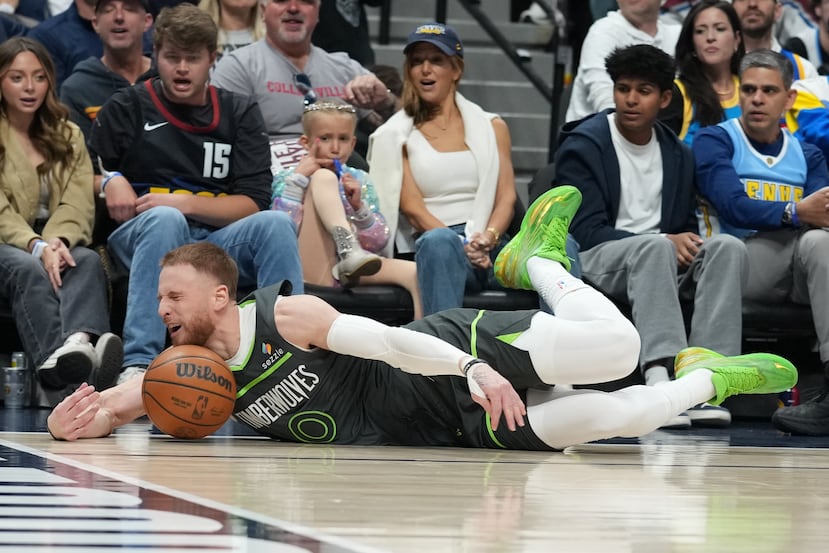 Minnesota Timberwolves guard Donte DiVincenzo slides across the floor while trying to save the ball from going out of play in the second half in Game 1 of a first-round NBA playoffs basketball series against the Denver Nuggets Saturday, April 18, 2026, in Denver. (AP Photo/David Zalubowski)