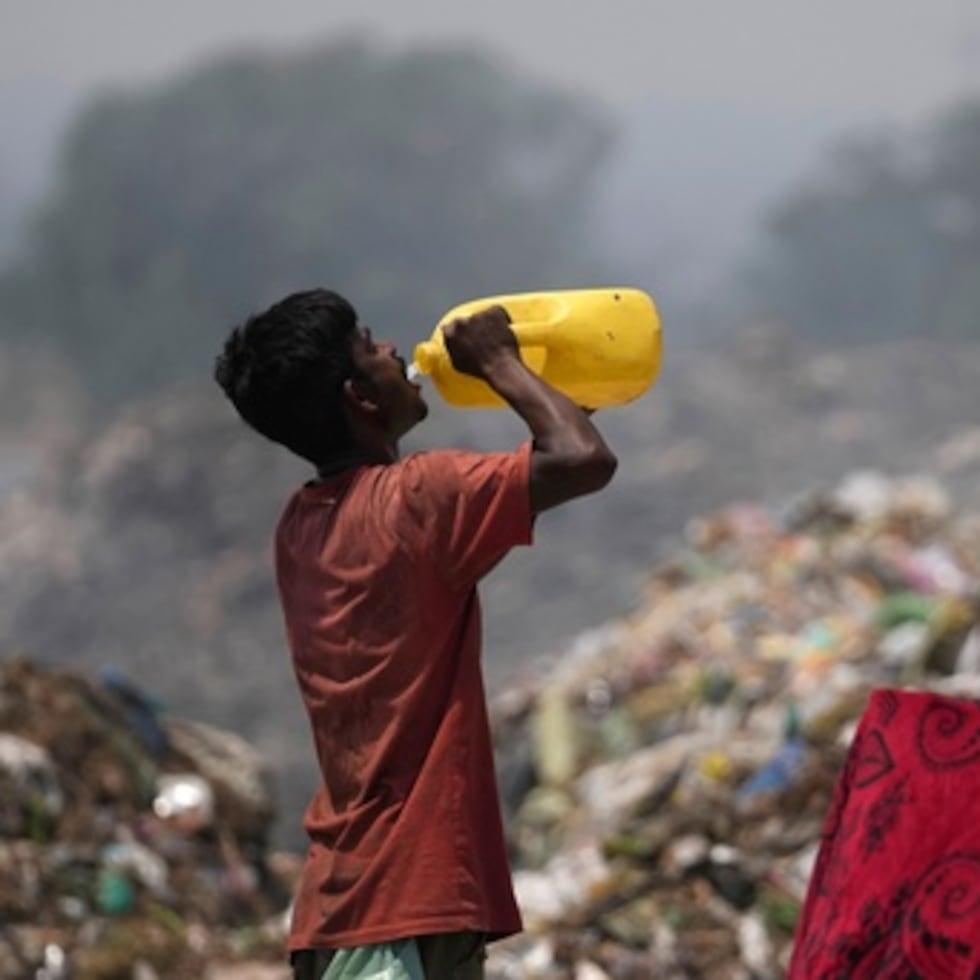 Un reciclador bebe agua mientras trabaja durante una ola de calor en un vertedero de basura en las afueras de Jammu, India.