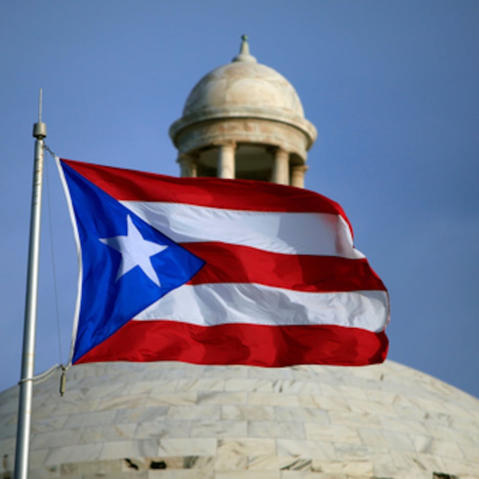 Una bandera puertorriqueña ondea frente al Capitolio en San Juan, Puerto Rico, 29 de julio de 2015. (Foto AP/Ricardo Arduengo, Archivo)