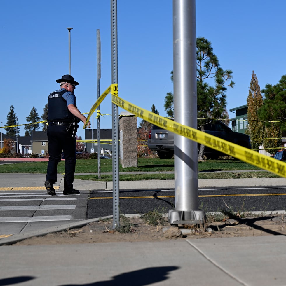 Un agente coloca cinta policial frente a la escuela primaria Silver Rail, donde ocurrió un tiroteo, el jueves 15 de octubre de 2026, en Bend, Oregon.