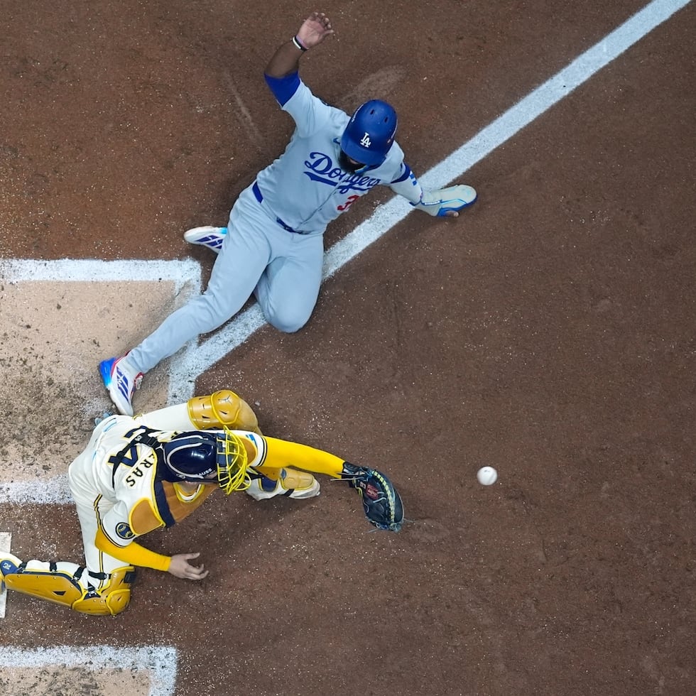 Teoscar Hernández, de los Dodgers de Los Ángeles, es puesto out en el plato por el receptor de los Brewers de Milwaukee, William Contreras, quien recibió un tiro de relevo durante la cuarta entrada del primer juego de la Serie de Campeonato de la Liga Nacional, el lunes 13 de octubre de 2025, en Milwaukee. (AP Foto/Morry Gash)