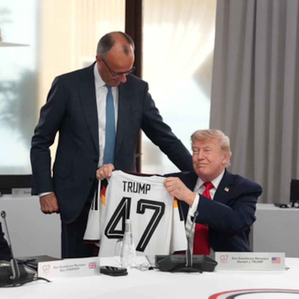 El presidente de Estados Unidos, Donald Trump, a la derecha, sostiene una camiseta con el número 47 mientras el primer ministro británico, Keir Starmer, a la izquierda, y el canciller alemán, Friedrich Merz, observan durante una sesión de trabajo en la cumbre del G7 celebrada en Evian-les-Bains, Francia.