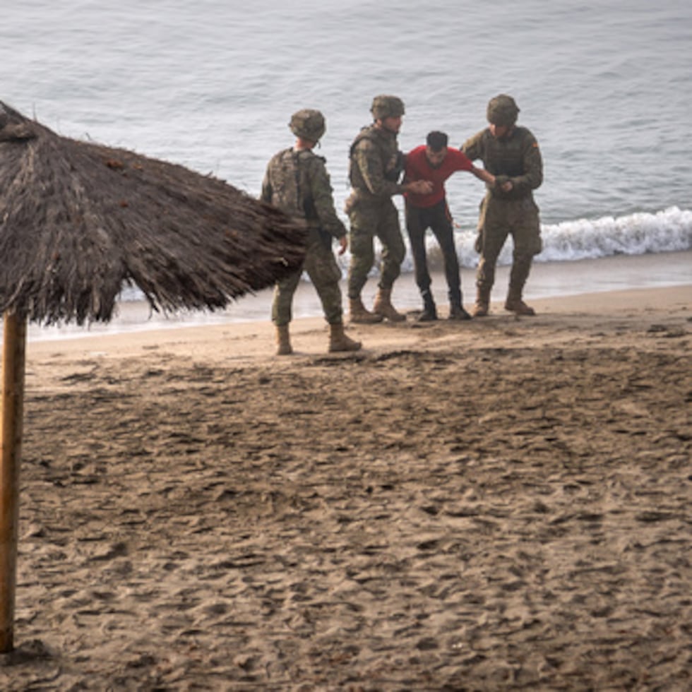 Soldados del ejército español prestan asistencia a un migrante que cruzó a nado desde Marruecos hasta el enclave español de Ceuta.