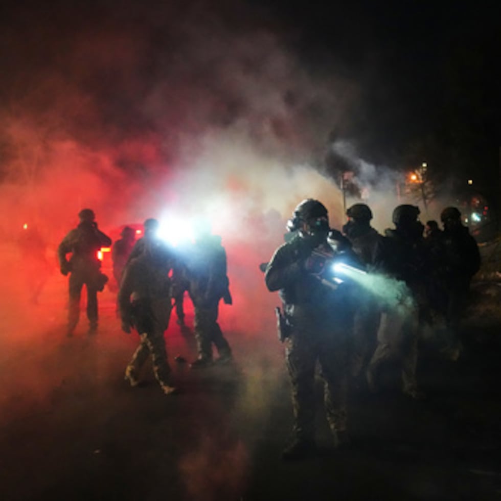 Agentes de la ley en medio de gases lacrimógenos en el lugar de un tiroteo en la noche del miércoles 14 de enero de 2026, en Minneapolis.