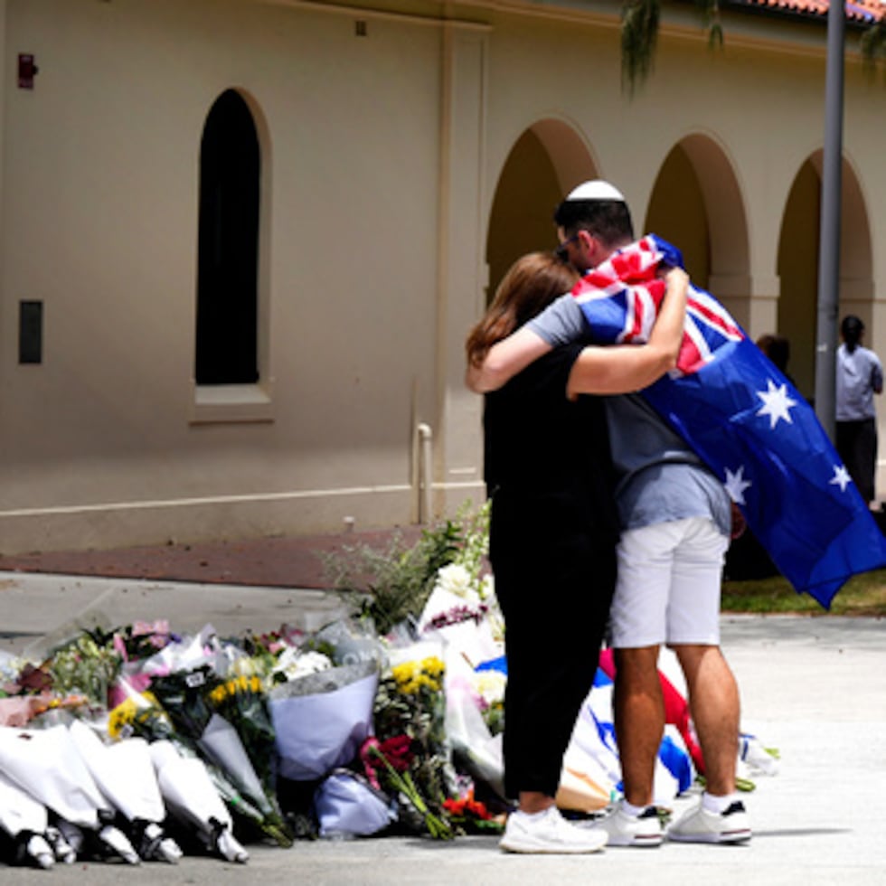 Una pareja deposita flores en un homenaje a las víctimas del tiroteo frente al Bondi Pavilion de la playa Bondi de Sídney, el lunes 15 de diciembre de 2025, un día después de un tiroteo. (AP Photo/Mark Baker)