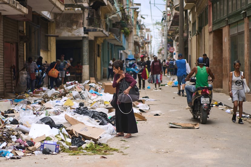 A pedestrian looks for items to salvage in a pile of trash on a street in Havana, Wednesday, April 22, 2026. (AP Photo/Ramon Espinosa)