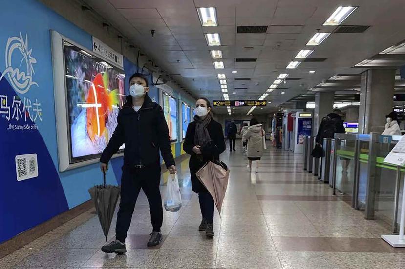 Unas personas usando un cubrebocas caminan por una estación de metro desierta en Shanghai, China. (AP)