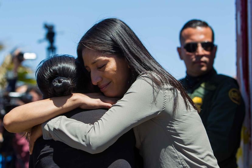Miembros de una familia se abrazan junto a un guardia fronterizo. (Agencia EFE)