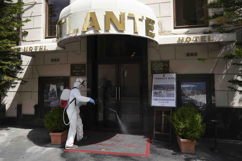 Un trabajador desinfecta la entrada del hotel Atlantic en Roma durante los días de emergencia por el coronavirus. (AP)