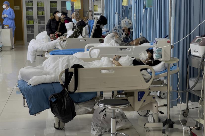 Las personas cuidan a sus familiares ancianos que reciben tratamiento médico en una sala de emergencias de un hospital en Beijing, el sábado 7 de enero de 2023.