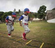 Dos niños corren durante un entrenamiento de béisbol en el centro deportivo Brisas de Petare, en Caracas, Venezuela. "Es triste reconocer que eso ha disminuido en gran cantidad la asistencia de muchachos", dijo Nelson Castro, que entrena a niños desde hac