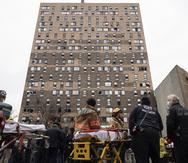 Personal de emergencias trabaja frente al  edificio de apartamentos que se incendió el domingo en el Bronx.