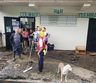 En las parcelas de Toita, en Cayey, varios vecinos limpian los deslizamiento de tierra frente a un negocio.